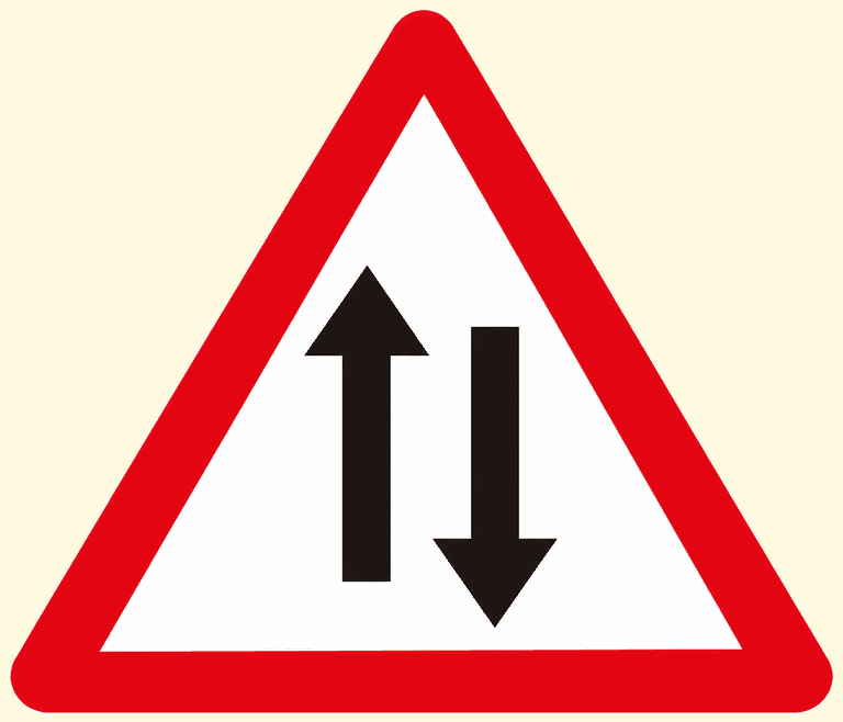 Red-bordered warning triangle containing one black arrow pointing up beside one pointing down: traffic runs in both directions ahead.